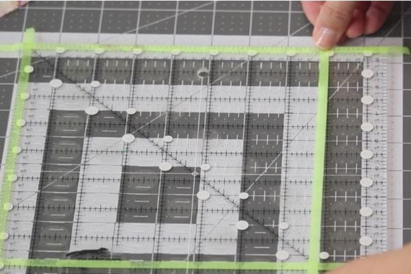 Image shows a cutting mat with a ruler laid on top. Hands are attaching glow tape to create a square.
