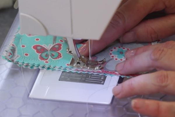 Image shows a sewing machine sewing the coaster pieces.