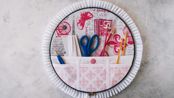 Image shows finished embroidery hoop organizer with tools inside the pockets.