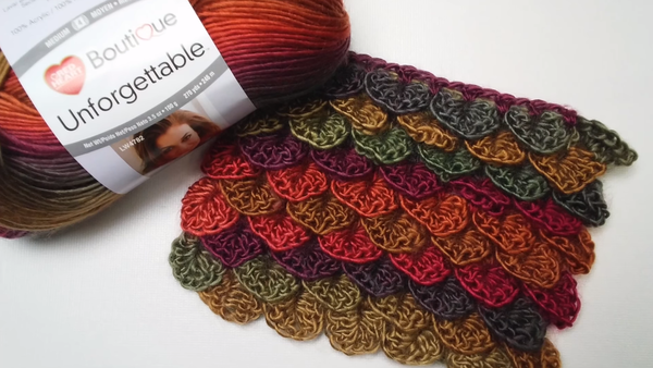 Image shows a skein of yarn on the left and a crocodile stitch crochet swatch in multiple colors.