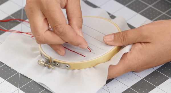 Image shows hands hand sewing using an embroidery hoop.