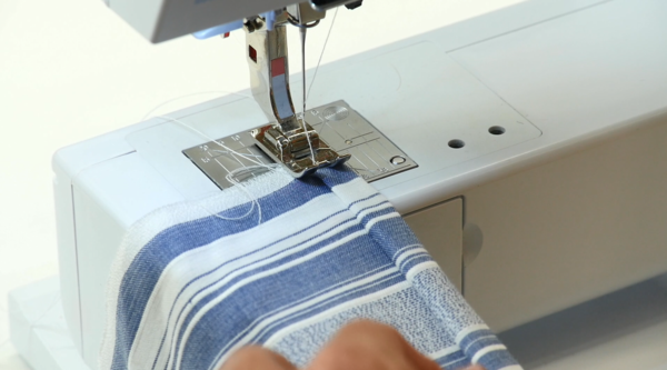 Image shows sewing the DIY kitchen boa fabric with a sewing machine.
