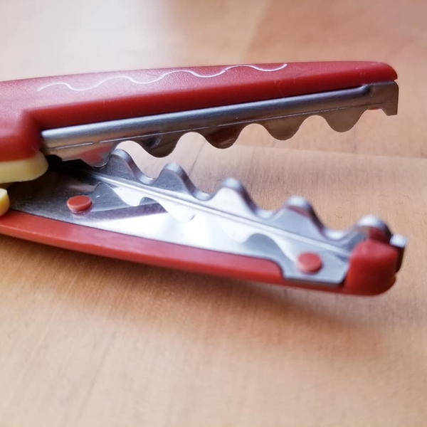Image shows a close-up of pinking shears sitting on a wood table.
