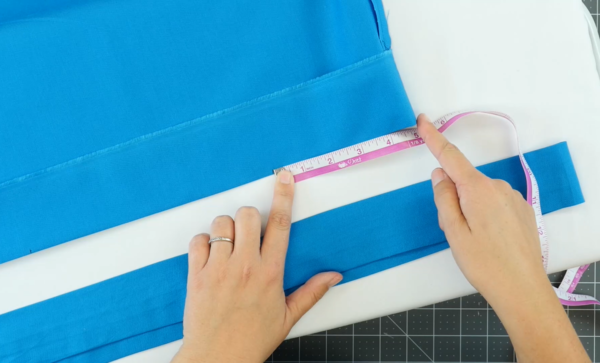 Image shows a white background and the blue fabric bag piece is being measured. There's also a separate strip of blue fabric.
