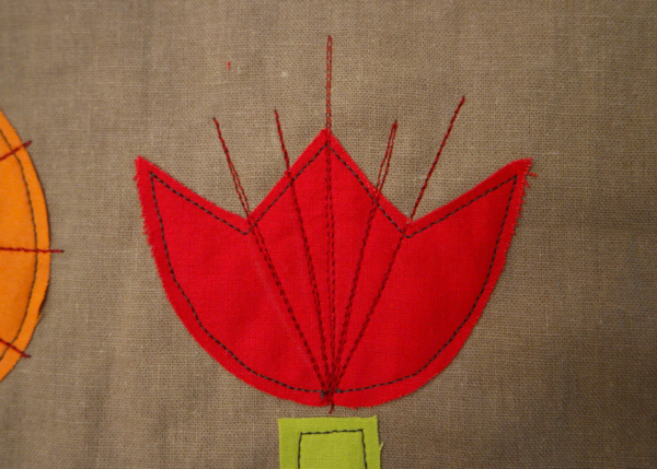 Image shows close-up of a red embroidered flower with four vertical lines added, on the cushion. How to Embroider the Flowers - Step 2
