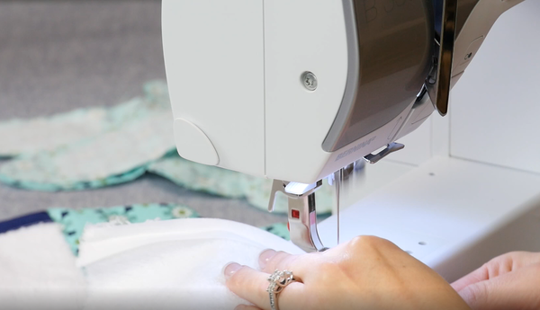 Image shows how to sew bias tape with a sewing machine around the terry cloth towel.