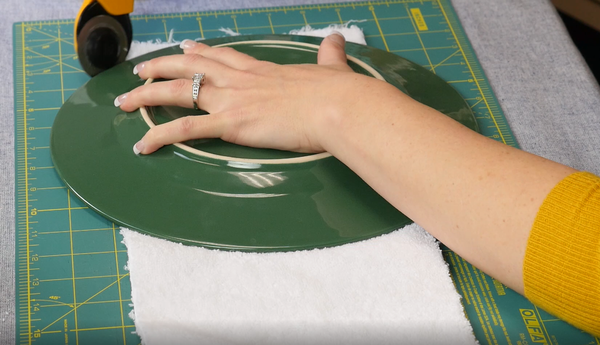 Image shows a plate being used to trim curved edges on the bottom of the terry cloth towel.
