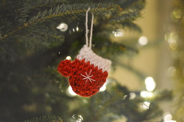 Image shows the Tunisian Mitten Ornament hanging on an evergreen tree.
