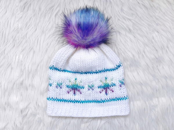 Image shows the I Wish It Would Snowflake Hat sitting on a light gray fur background.