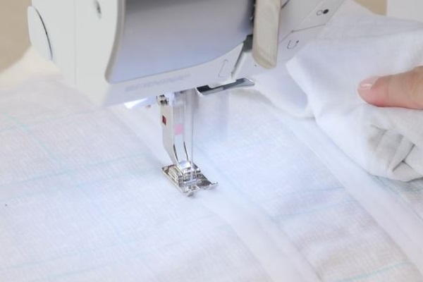 Image shows the another stitch to secure the Velcro being sewn with a machine to the piece of light fabric.