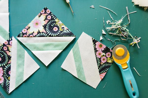 Image shows three quilt blocks and a rotary cutter.