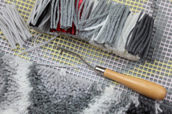 Image shows preparation to rug latch hook: canvas, cut yarns, latch-hook.