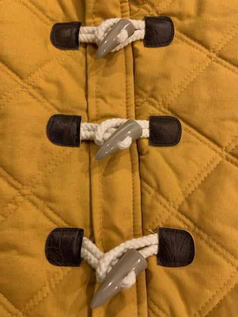 Images shows a close-up of a coat with three toggle closures.