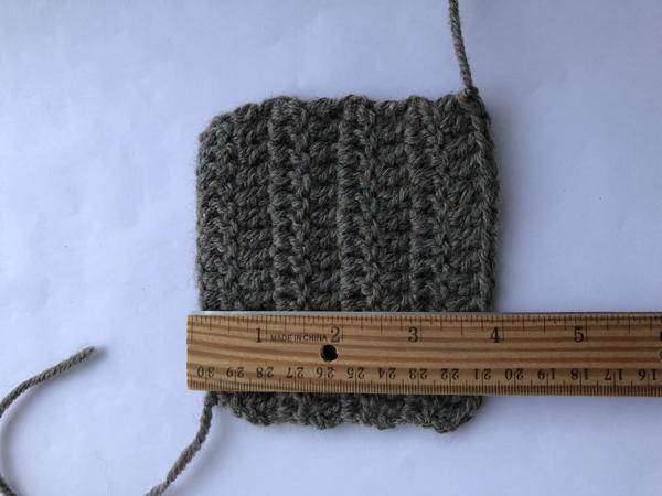 Image shows a crochet swatch on a light background. There is a wooden ruler measuring horizontally across.
