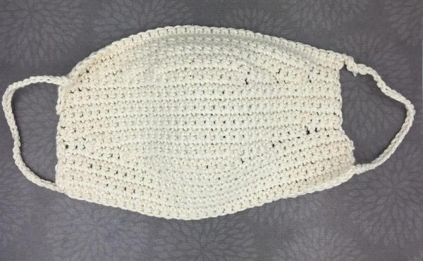 Image shows a white crochet mask on a gray background. Image shows a white crochet mask on a gray background.