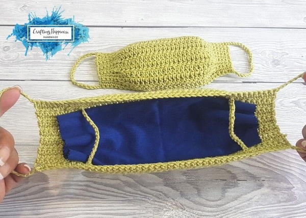 Image shows a wood background with two yellow masks shown. One is facing outward and one is being held showing the inside with a blue piece of fabric lining the mask. Image shows a wood background with two yellow masks shown. One is facing outward and one is being held showing the inside with a blue piece of fabric lining the mask.