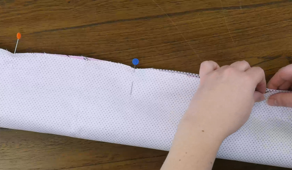 Image shows a person pinning fabric for a sewing project.