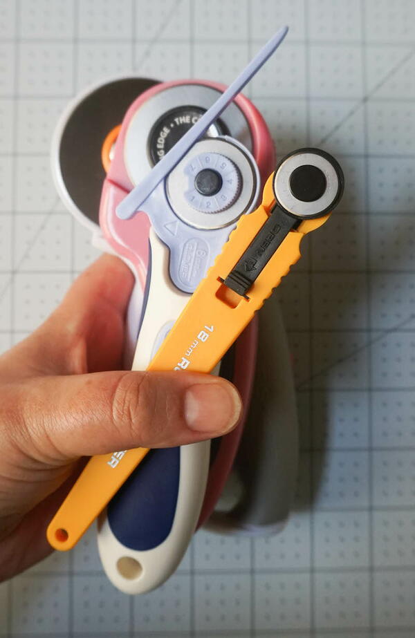 Image shows a hand holding multiple rotary cutters.