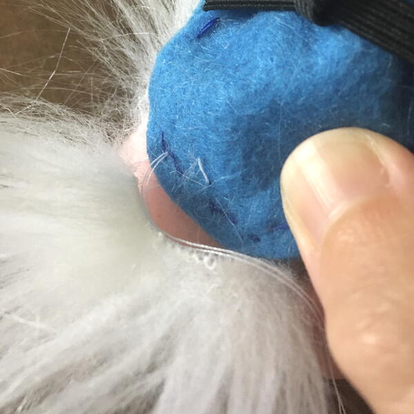 Image shows the blue felt body being sewn to the beard for the DIY Gnome Ornament.