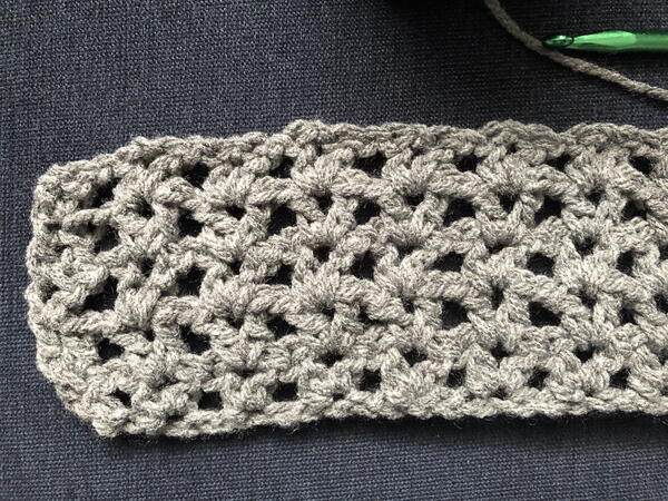 Image shows a close-up of the start of a v-stitch blanket in gray.