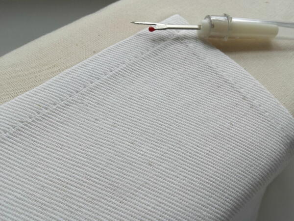 Image shows resulting look of fabric after removing stitches, pressing, and using a nail and spoon to help close up holes.