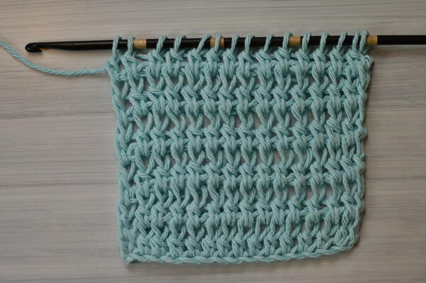 Image shows the continued progress for the Tunisian double crochet piece.