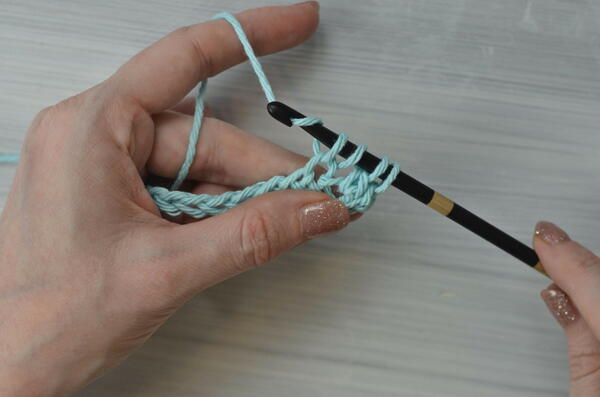 Image shows yarning over for the Tunisian double crochet piece.