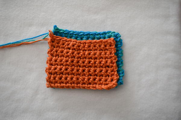 Both swatches are (4) medium/worsted weight, but the blue-green swatch is much larger than the orange swatch.