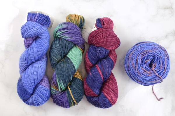 Image shows three hanks of yarn on the left and a cake of yarn on the right.