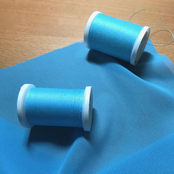 Image shows blue fabric and two spools of matching blue thread