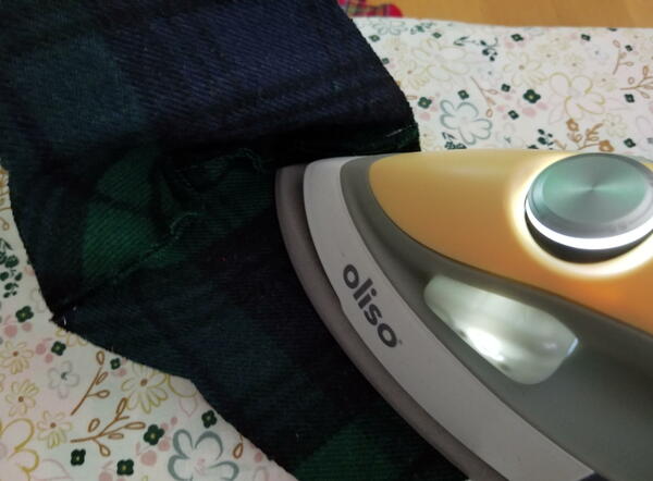 Ironing Tips for Beginners: Oliso iron pressing fabric on an ironing board.