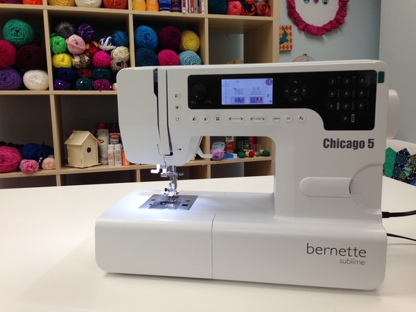 Image shows a sewing machine sitting on a table in a craft room.