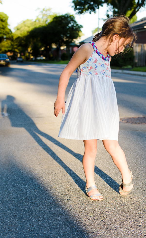 Image shows a girl standing on a street wearing the Little Lady Braided Dress.