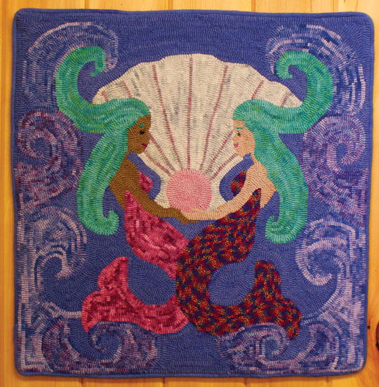 Image shows the Treasure of the Sea design: two mermaids face-to-face with a giant shell in between them.