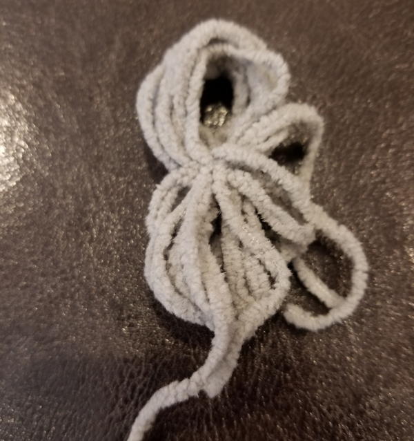 Image shows the wrapped and tied pieces of yarn no longer on the hand (step 2).