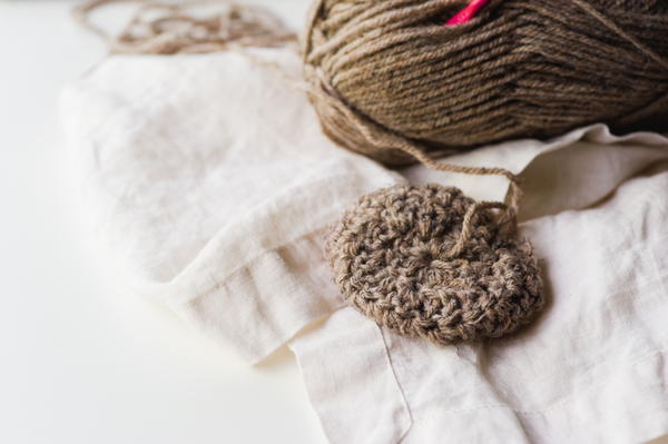 Image shows a skein of brown yarn and a crocheted circle.