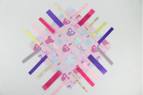 Image shows a square piece of fabric with unfolded ribbons arranged around all four sides.