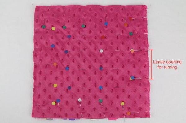 Image shows the blanket fabric piece (with the other underneath, not showing) with several pins. There is text that states, "Leave opening for turning".
