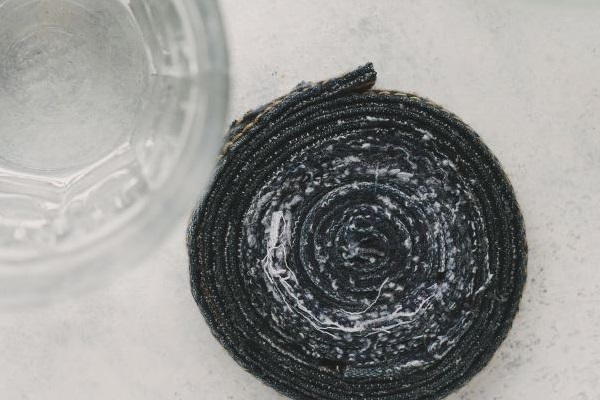 Image shows, from above, the finished rolled jean coaster sitting on a table next to a glass.