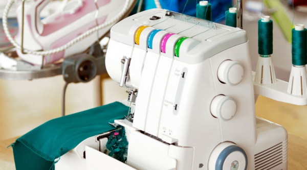 Image shows a serger sewing machine on a table and is from our article: What is a Serger?