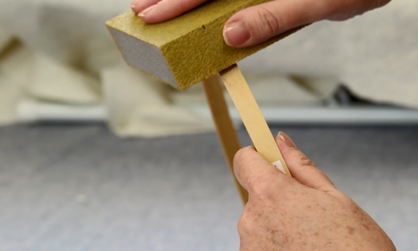 Image shows hands holding and sanding an embroidery hoop.