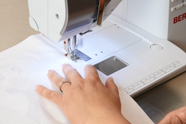 Image shows a close up of a sewing machine sewing the blocks together.