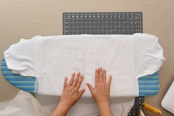 Image shows a piece of fusible interfacing atop the cut shirt lying on a small ironing board.