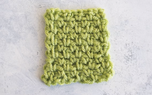 Image shows a green yarn swatch made using the moss stitch.