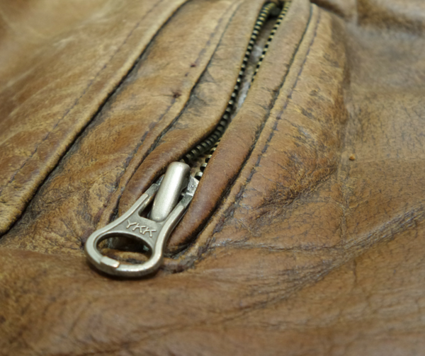 Image shows a close-up of a zippered pocket on a leather garment.