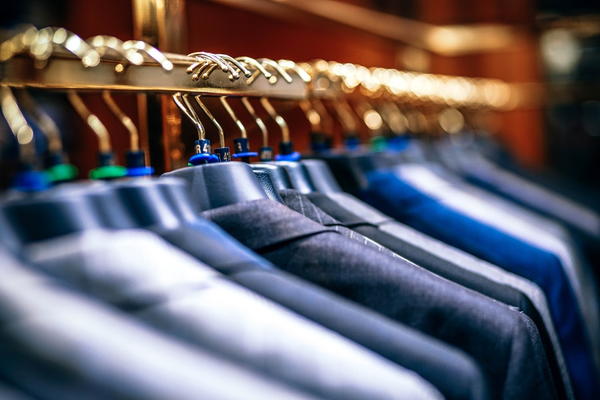 Image shows a close-up of a closet with suit jackets hanging on hangers.