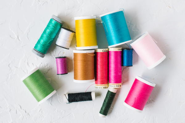 Image shows various spools of thread in different colors and sizes laying down on a light background.