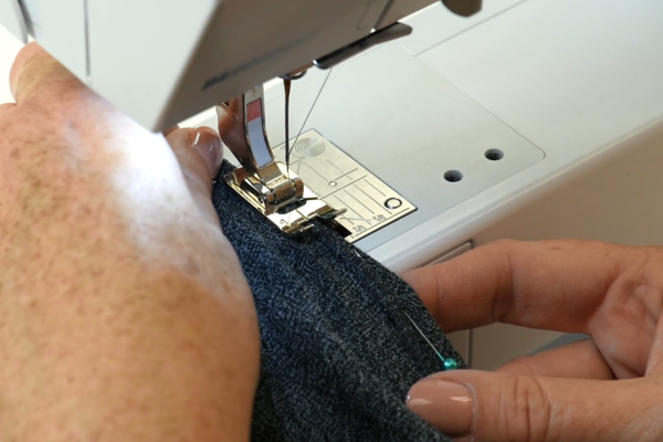 Image shows Mary Beth sewing the shirt where pinned. This is done on a sewing machine using narrow or short zig-zag stitch. A serger machine can also be used.