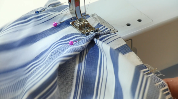 Image shows the pinned towel fabric being sewn with a machine.