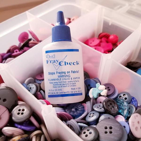 Image shows a bottle of Fray Check sitting in a container of buttons.